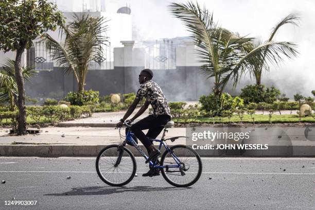 Man rides his bicycle past clouds of tear gas as scuffles broke out at the Cheikh Anta Diop University in Dakar on March 29, 2023. - A new round of...
