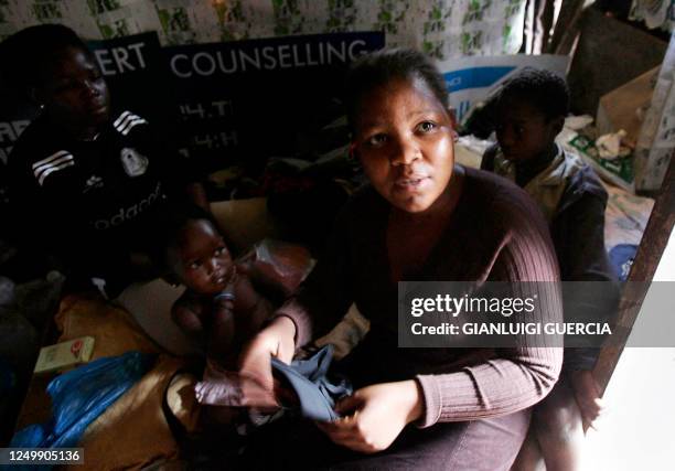 Woman and her family rest after work in a small house in one of central Durban's slums, 21 December 2005. From the slums of Durban, a new movement is...