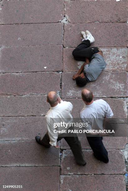 Dos hombres observan a un nino que duerme en una calle del centro de Montevideo, el 02 de febrero de 2006. En 2005 mas de 2000 menores infractores...