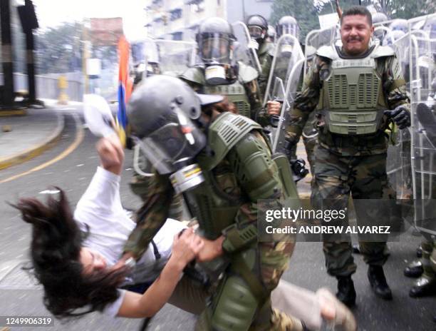 Member of a riot squad of the militarized National Guard of Venezuela struggles with an activist who participated in an opposition rally near the...