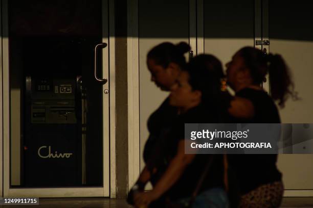 Salvadoran women walk in front of a store that protects an ATM of the Chivo state bitcoin wallet in different places on March 29, 2023 in San...