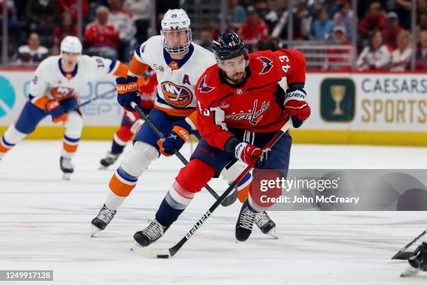 Tom Wilson of the Washington Capitals skates the puck up the ice as he is pressured by Brock Nelson of the New York Islanders at Capital One Arena on...