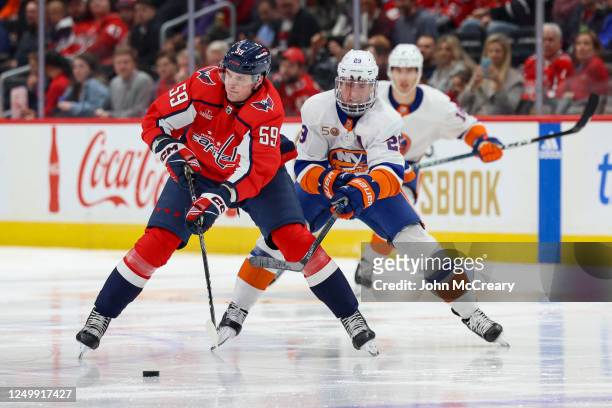 Aliaksei Protas of the Washington Capitals controls the puck as he is pursued by Brock Nelson of the New York Islanders during a game at Capital One...
