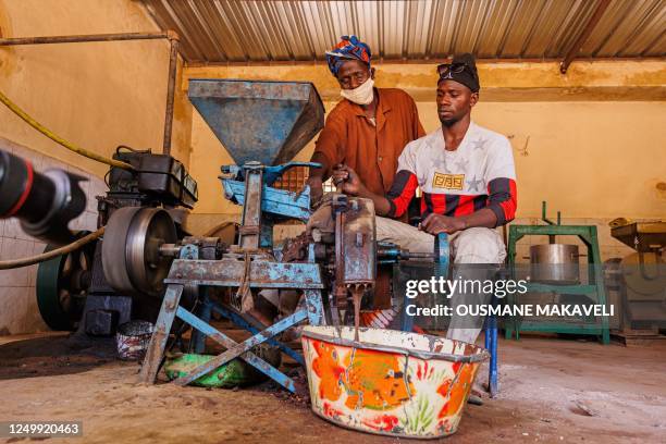 Man uses a machine to grind shea nuts into a paste, which will be used to make Karite butter in Siby on March 21, 2023. - Shea, a tree indigenous to...