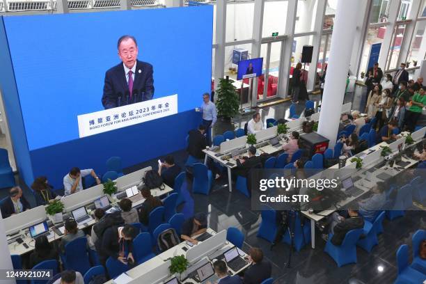 Journalists watch a screen showing Ban Ki-moon, former UN Secretary General and Chairman of the Boao Forum for Asia, delivering a speech during the...