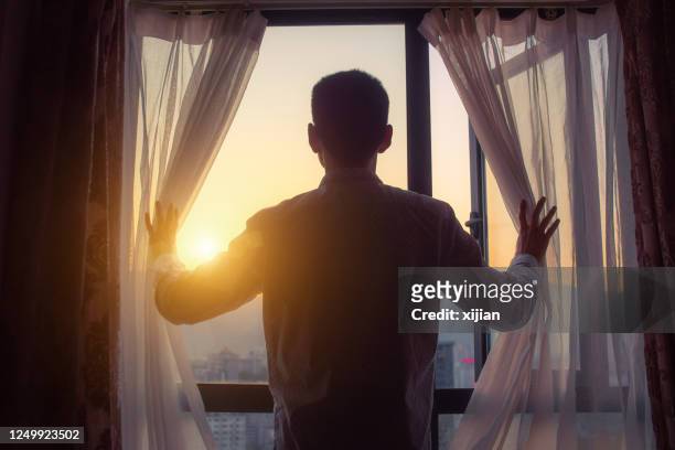 uomo d'affari che guarda l'alba in piedi vicino alla finestra - alba crepuscolo foto e immagini stock