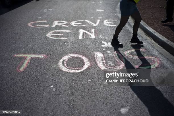 Woman walks past en inscription "Tous en greve" written on the road as part of the demonstrations of railway workers from state-run company SNCF...