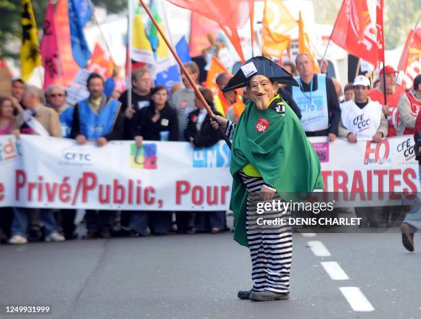 Man wears a mask representing French President Sarkozy as people demonstrate on October 12, 2010 in Lille northern France, to protest against...