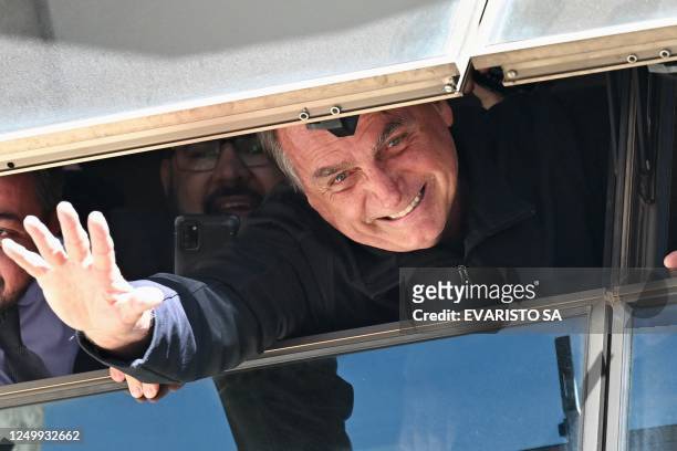 Former Brazilian president Jair Bolsonaro greets supporters from a window at the Liberal Party headquarters of n Brasilia on March 30, 2023. -...