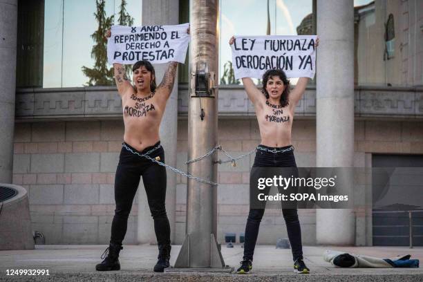 Two topless Femen activists hold banners expressing their opinion while chained at the Senate headquarters to protest against the approval of the Gag...