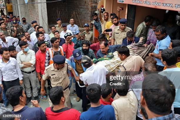 Rescue and security personnel carry a devotee on a stretcher who was injured after the floor covering a stepwell collapsed at a temple in Indore on...