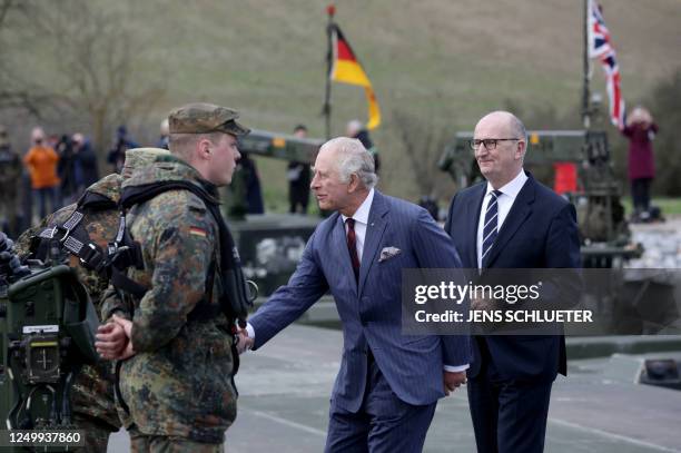 Brandenburg's State Premier Dietmar Woidke looks on as Britain's King Charles III shakes hands with soldiers during his visit at the 130th...