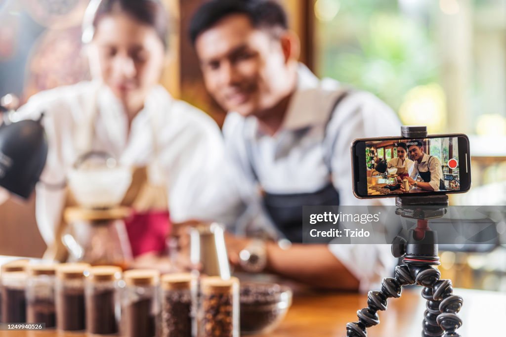 Mobile phone taking Video to two Asian Barista presenting a cup of coffee, dripping coffee show to audience in coffee shop,making espresso and americano, Small business owner and startup concept