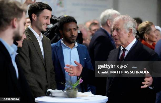 Britain's King Charles III speaks with guests as he visits an organic farm with milking parlour and cow shed in Brodowin, eastern Germany, on March...