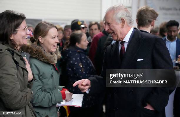 Britain's King Charles III speaks with guests as he visits an organic farm with milking parlour and cow shed in Brodowin, eastern Germany, on March...