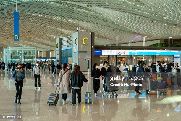 Passengers with luggages walk and wait check-in at Incheon International Airport on March 30 South Korea. According to Incheon International Airport...