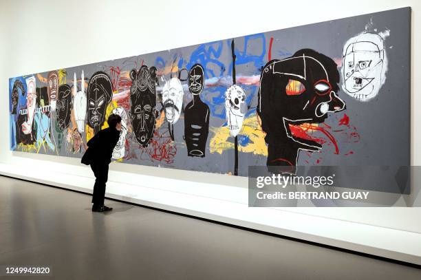 Visitor looks at "Arican Masks", an acrylic painting made ca. 1984-1985 by US Neo-expressionism artist Jean-Michel Basquiat and US artist, film...