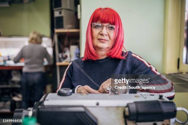 mature woman putting new thread on sewing machine - older woman colored hair stock pictures, royalty-free photos & images