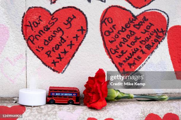 Red hearts painted in memory of people who have died of Covid-19 during the coronavirus pandemic at the National Covid Memorial Wall and flowers laid...