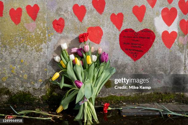 Red hearts painted in memory of people who have died of Covid-19 during the coronavirus pandemic at the National Covid Memorial Wall and flowers laid...