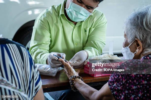 Nurse is checking the blood sugar of an elder person who is living in Rong Moo community, an underprivileged area of Bangkok, during the charity...