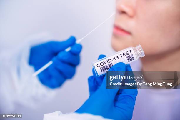 doctor in protective gloves & workwear holding testing kit for the coronavirus test - coronavirus test stock-fotos und bilder