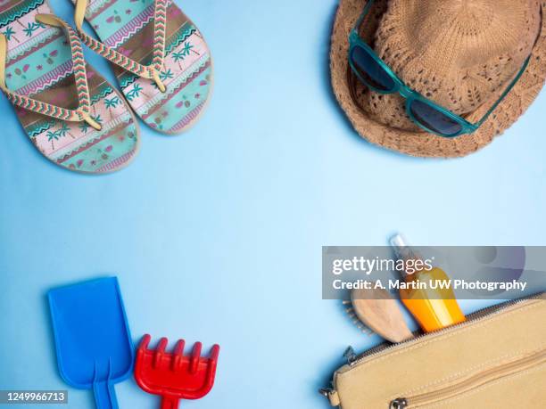 beach stuff. beach toys (shovel and plastic rake), flip flops, hat, sunglasses and bag with brush and suntan lotion on a light blue background - red flip flops isolated stock pictures, royalty-free photos & images