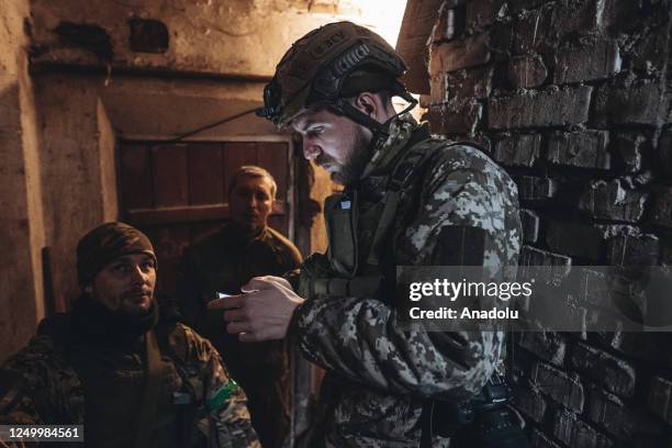 Ukrainian soldiers look at the mobile phone in a cellar near Bakhmut, Ukraine on March 29, 2023.