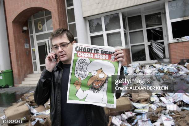 The Charlie Hebdo's publisher, known only as Charb, uses his cell phone as he shows a special edition of French satirical magazine Charlie Hebdo on...