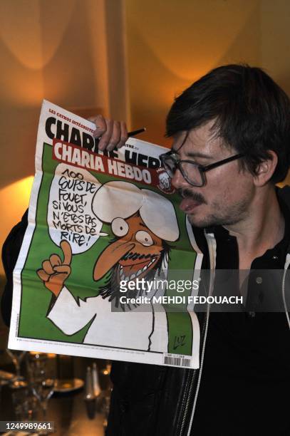 The Charlie Hebdo' s cartoonist Luz sticks out his tongue as he shows a special edition of French satirical magazine Charlie Hebdo, on November 3,...