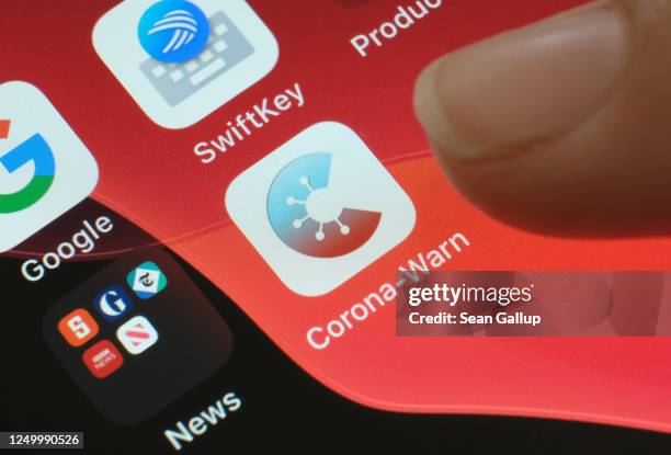 In this photo illustration the photographer's daughter moves her finger towards the newly-released "Corona-Warn-App" developed by the German...