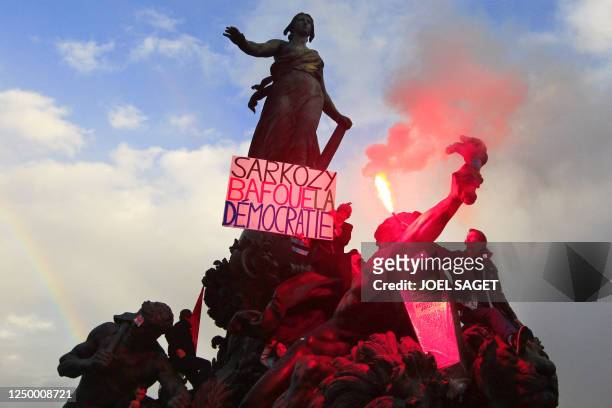 Men hold a placard reading " Sarkozy mockes the democratie " and a flare on on the "Triomphe de la Republique" sculpture, on October 16, 2010 at the...