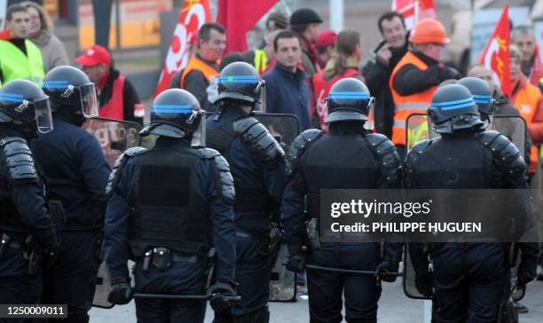 Anti riot policemen stand in front of striking workers who block the entrance of the National wholesale Market of Lomme near Lille, northern France,...