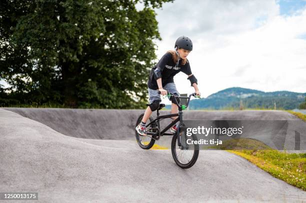 young girl riding bmx bicycle - bmx cycling stock pictures, royalty-free photos & images