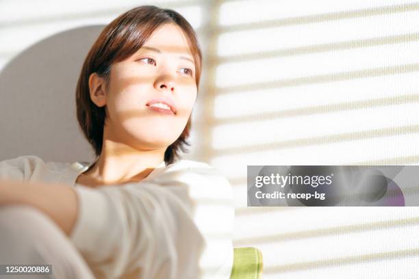 portrait of young woman lit by bright day sunlight at home - brightly lit imagens e fotografias de stock