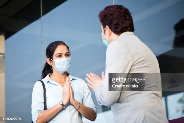 businesswoman greeting businessman avoiding handshakes - respect stock pictures, royalty-free photos & images