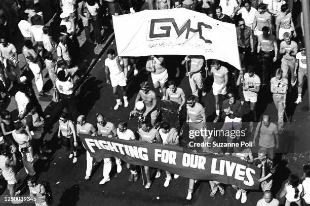 View, from above, of onlookers and marchers, with a GMHC banner and another that reads 'Fighting for Our Lives,' on Christopher Street during the...