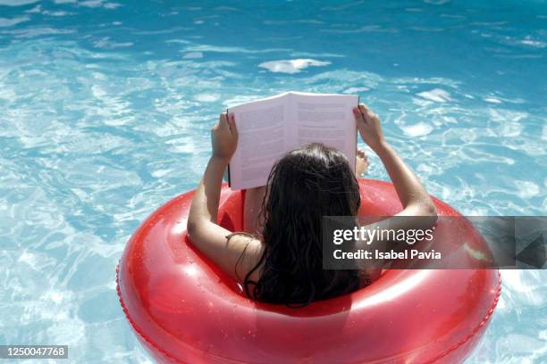 relaxed woman reading in swimming pool - red tube 個照片及圖片檔