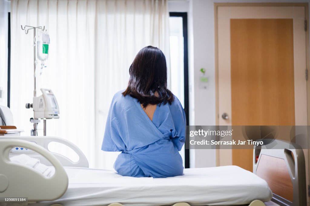 Young women sitting up in the hospital bed and looking through the window