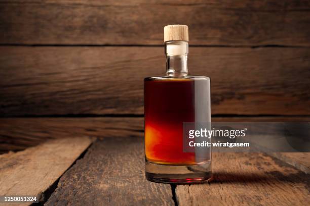 close-up of whiskey bottle on wooden table against wooden wall. - bottiglia vetro foto e immagini stock