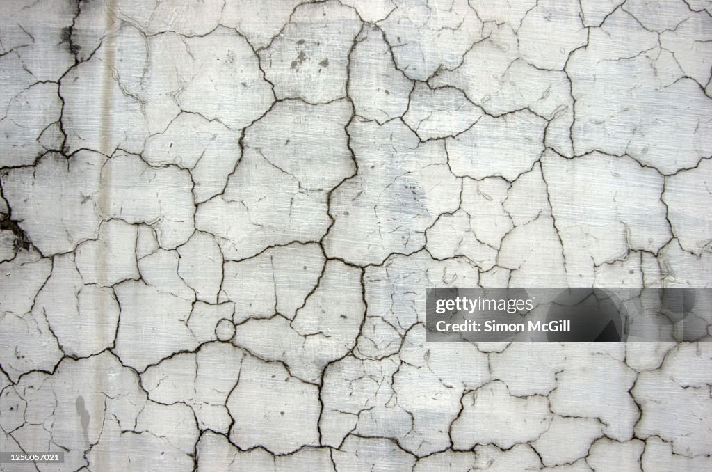Damp, cracked and weathered grey concrete wall