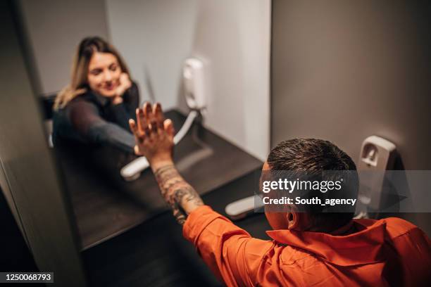 young woman and her husband sitting in visiting room - prison visit stock pictures, royalty-free photos & images