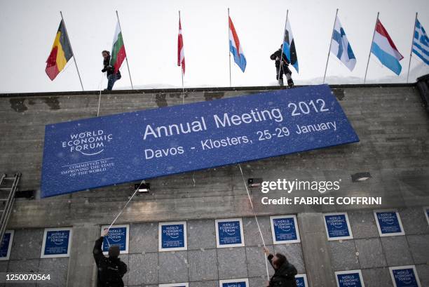 Employees install a sign of the World Economic Forum on the Congress Center in the Swiss resort of Davos on January 23, 2012. Some 1,600 economic and...