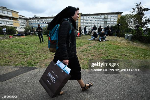 Nun walks past the Gemelli hospital as television reporters wait behind on March 31, 2023 in Rome, two days after the Pope was admitted to the...