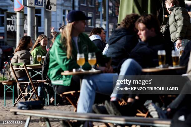 Customers drink and eat at a terrace in the center of Amsterdam on March 30, 2023.