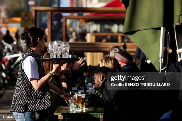 Waitress works as customers drink at a terrace in the center of Amsterdam on March 30, 2023.