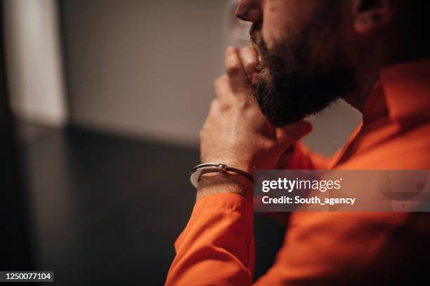 gevangene in oranje jumpsuitzitting in gevangenis bezoekende ruimte - jail room stockfoto's en -beelden