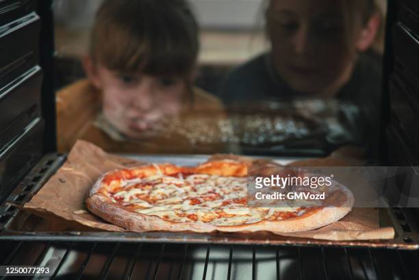kleine mädchen backen pizza im ofen - backofen stock-fotos und bilder