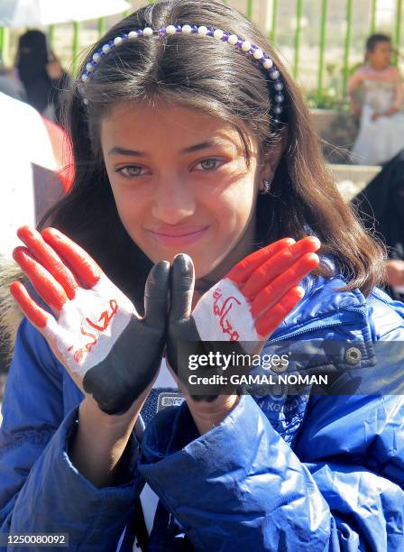Yemeni girl with the Yemeni colors and the word "trial" painted on her hands joins anti-regime protesters demonstrating against outgoing President...