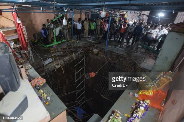 In this picture taken on March 30 rescue teams and officials gather around the perimeter of the collapsed floor area that was covering a stepwell...